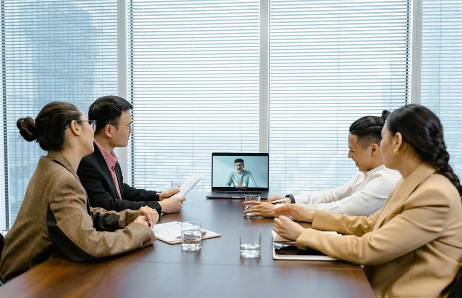 Corporate team attending an online conference with a remote participant on a laptop